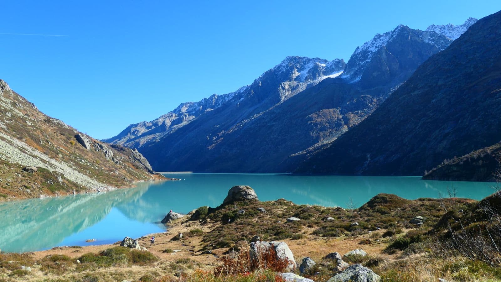 A still alpine lake beneath snow-touched peaks